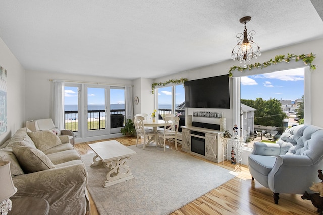 1 Seacliff Ave Unit 3D, Old Orchard Beach, ME 04064 - living room with wood finished floors, a glass covered fireplace, a chandelier, and a textured ceiling