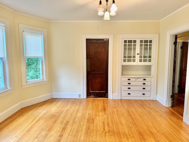 91 Washburn Ave, Portland, ME 04102 - unfurnished bedroom with light wood-type flooring, a chandelier, ornamental molding, and baseboards