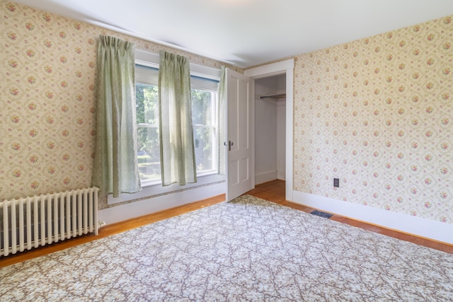 10 Joslyn St, Newport, ME 04953 - unfurnished bedroom featuring radiator, wood finished floors, wallpapered walls, baseboards, and a closet