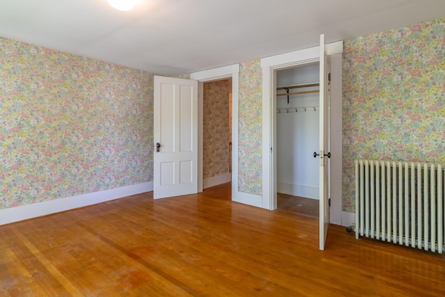 10 Joslyn St, Newport, ME 04953 - unfurnished bedroom with radiator, wood finished floors, wallpapered walls, a walk in closet, and baseboards