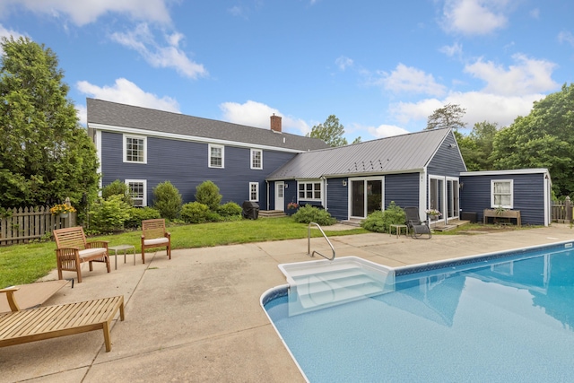 179 Alfred Rd, Kennebunk, ME 04043 - back of house featuring a patio area, entry steps, a chimney, an outdoor pool, and a metal roof