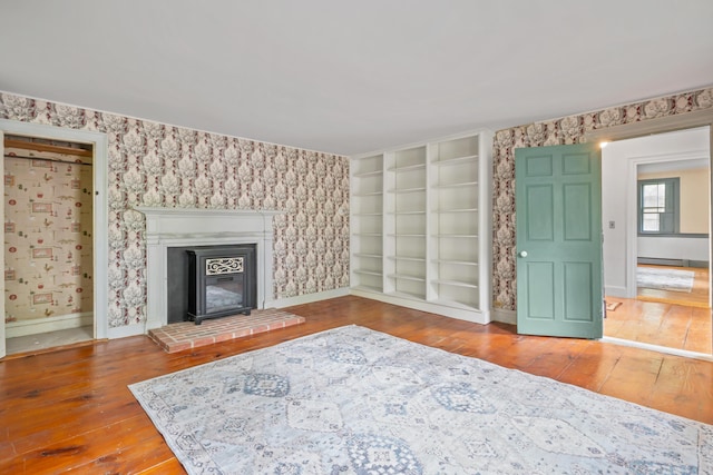 74 Main St, Cornish, ME 04020 - unfurnished living room with hardwood / wood-style flooring, baseboards, a glass covered fireplace, a baseboard heating unit, and wallpapered walls