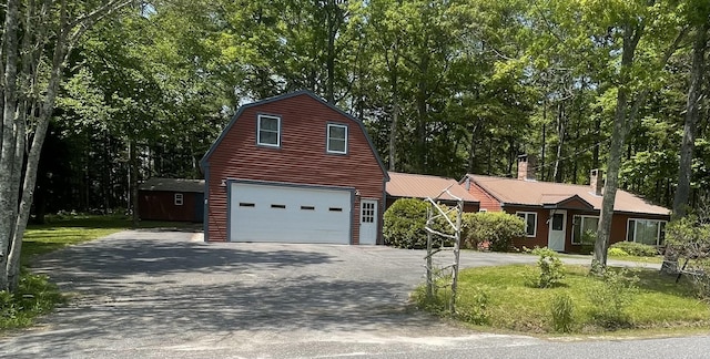 386 Lower Flying Point Rd, Freeport, ME 04032 - dutch colonial featuring asphalt driveway, an attached garage, a chimney, a gambrel roof, and an outdoor structure