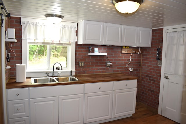 140 Station Rd, Lincoln, ME 04457 - kitchen featuring a sink, butcher block counters, brick wall, white cabinets, and wood finished floors