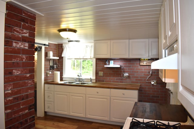 140 Station Rd, Lincoln, ME 04457 - kitchen with a sink, wooden counters, white cabinets, light wood-type flooring, and brick wall