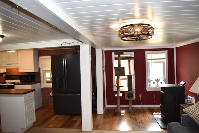 140 Station Rd, Lincoln, ME 04457 - kitchen with black fridge, under cabinet range hood, light wood-style floors, and butcher block counters