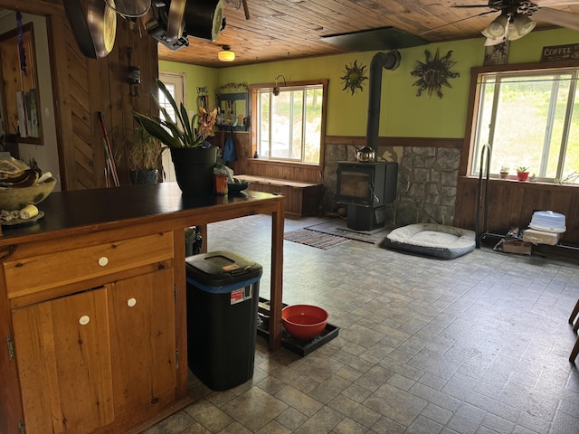 20 Coldbrook Rd, Hampden, ME 04444 - kitchen featuring a wainscoted wall, ceiling fan, wood ceiling, a wood stove, and wooden walls