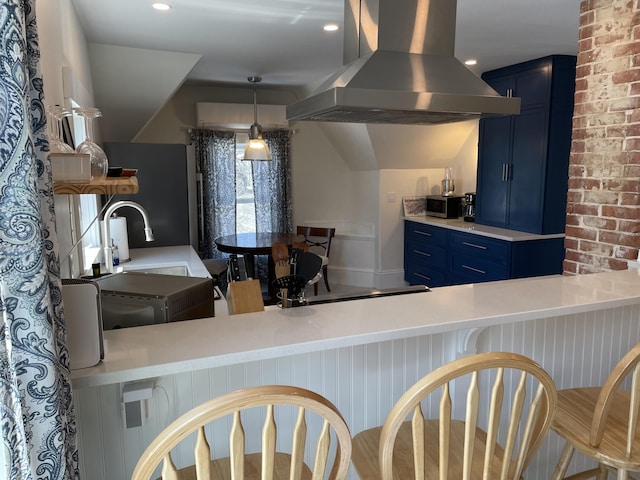 138 Limerock St Unit A, Rockland, ME 04841 - kitchen with blue cabinetry, island exhaust hood, a kitchen bar, stainless steel microwave, and light countertops