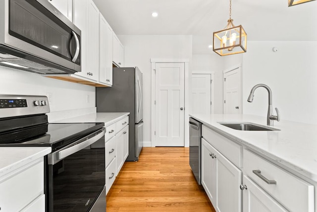 21 Arnies Alley -, Westbrook, ME 04092 - kitchen featuring appliances with stainless steel finishes, a sink, white cabinetry, light wood-style floors, and a chandelier