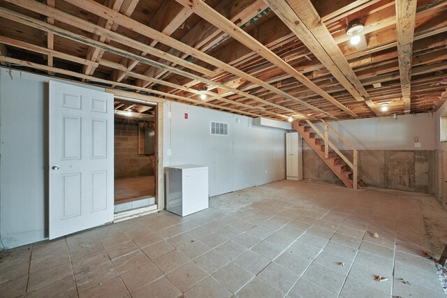 33-34 Gerber Ln, Monmouth, ME 04259 - below grade area featuring stairs, electric panel, tile patterned floors, and refrigerator