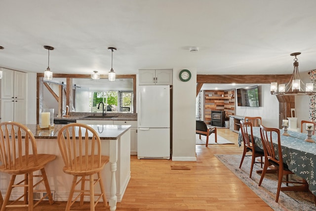 33-34 Gerber Ln, Monmouth, ME 04259 - kitchen featuring freestanding refrigerator, a kitchen bar, light wood-type flooring, white cabinets, and pendant lighting
