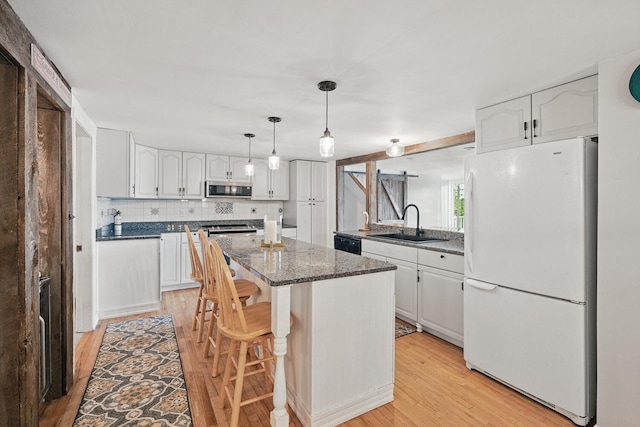 33-34 Gerber Ln, Monmouth, ME 04259 - kitchen with freestanding refrigerator, stainless steel microwave, light wood-style flooring, a kitchen island, and white cabinetry