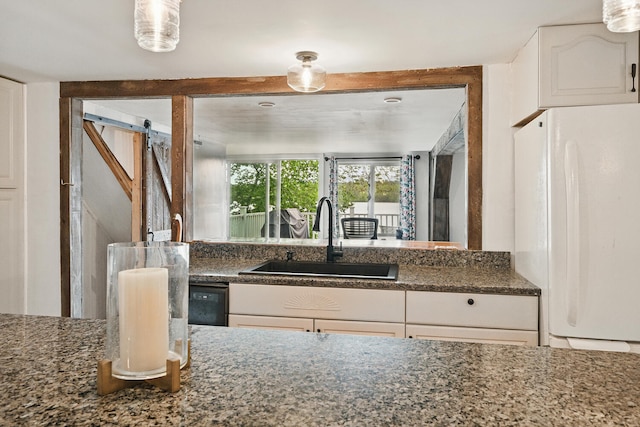 33-34 Gerber Ln, Monmouth, ME 04259 - kitchen featuring freestanding refrigerator, a barn door, white cabinets, and dark stone counters