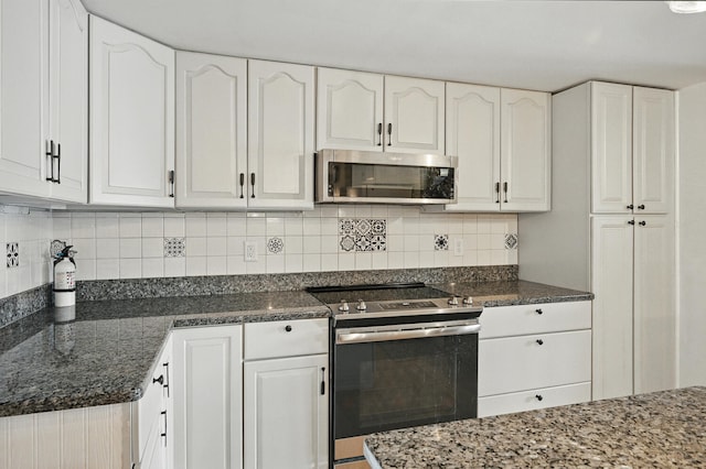 33-34 Gerber Ln, Monmouth, ME 04259 - kitchen with stainless steel appliances, white cabinetry, dark stone countertops, and decorative backsplash