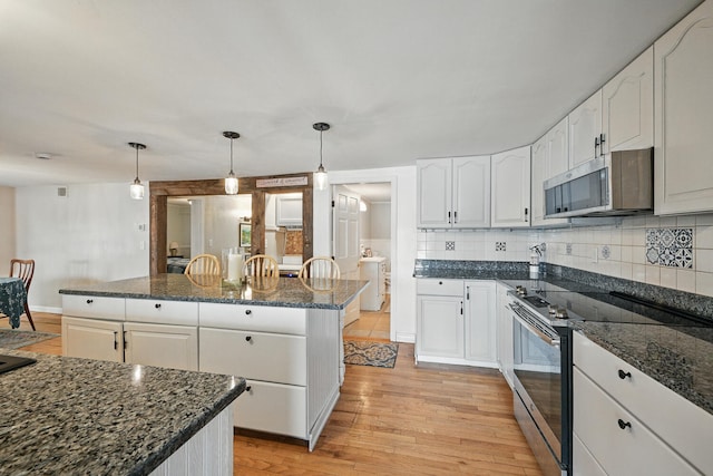 33-34 Gerber Ln, Monmouth, ME 04259 - kitchen featuring appliances with stainless steel finishes, light wood-type flooring, white cabinets, decorative backsplash, and a kitchen island