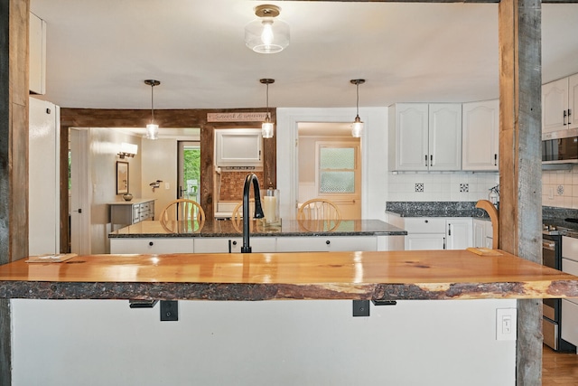 33-34 Gerber Ln, Monmouth, ME 04259 - kitchen with tasteful backsplash, stainless steel microwave, white cabinetry, pendant lighting, and butcher block countertops