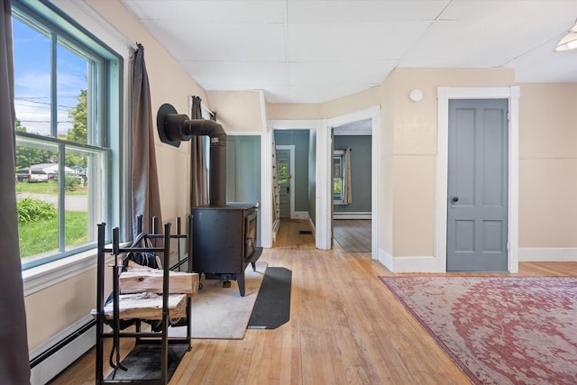 133 Front St, Old Town, ME 04468 - exercise area with baseboard heating, a baseboard radiator, a wood stove, and light wood-style floors