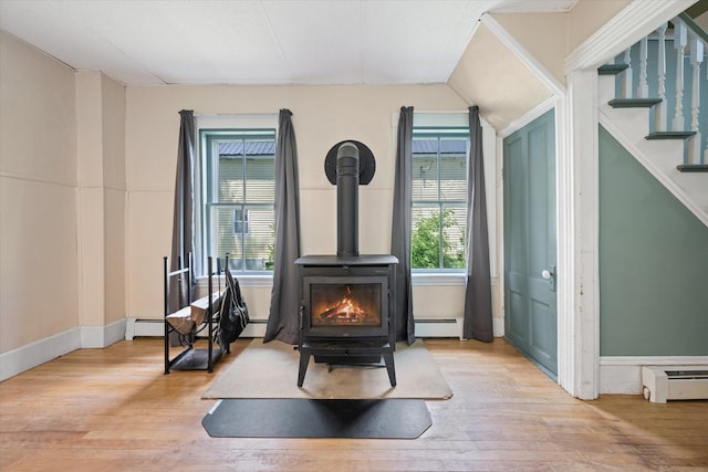 133 Front St, Old Town, ME 04468 - detailed view of a wood stove, wood finished floors, a baseboard heating unit, and a baseboard radiator