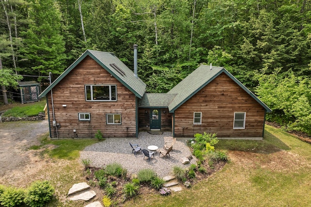 12 Michaud Ln, Bridgton, ME 04009 - rear view of house with a fire pit, a patio area, a yard, a wooded view, and roof with shingles