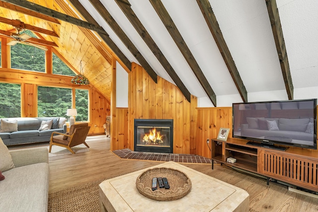 12 Michaud Ln, Bridgton, ME 04009 - living area with wood finished floors, a glass covered fireplace, wooden walls, and ceiling fan