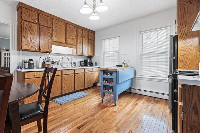 22 Union St, Biddeford, ME 04005 - kitchen featuring a baseboard heating unit, stove, a sink, brown cabinets, and a textured ceiling