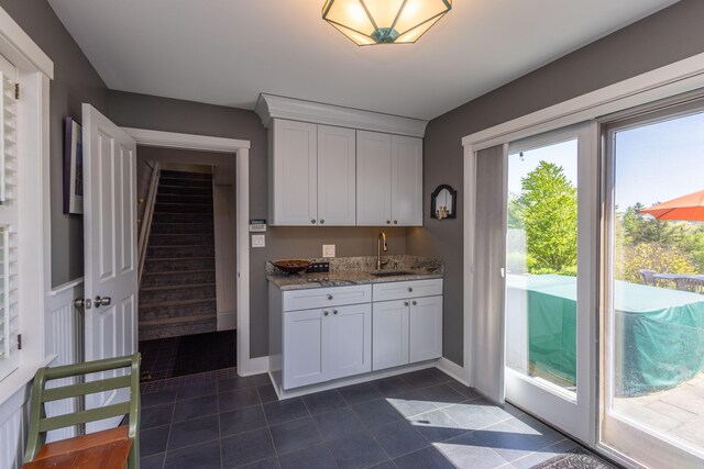 321 Beech Hill Rd, Northport, ME 04849 - kitchen featuring a sink, light stone counters, dark tile patterned flooring, white cabinetry, and baseboards