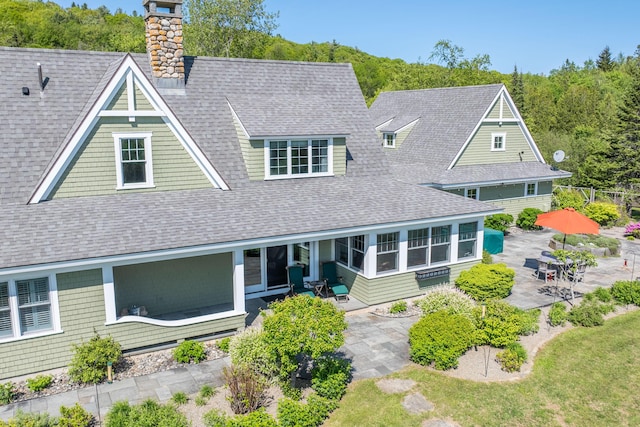 321 Beech Hill Rd, Northport, ME 04849 - shingle-style home featuring a patio, a shingled roof, and a chimney