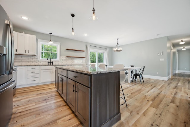 45 Doughty Blvd, Levant, ME 04456 - kitchen featuring stainless steel fridge, a breakfast bar, light wood-type flooring, white cabinets, and recessed lighting
