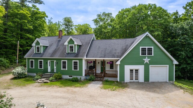 310 Fields Hill Rd, Sumner, ME 04292 - cape cod house with driveway, covered porch, a garage, a chimney, and view of wooded area