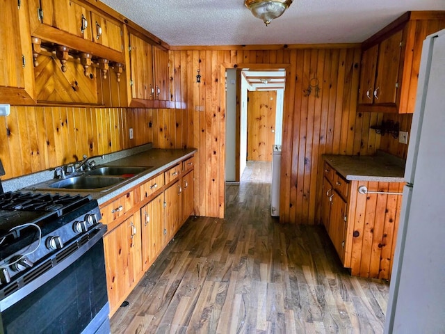 230 Todds Corner Rd, Saint Albans, ME 04971 - kitchen featuring black gas range, a sink, brown cabinetry, dark wood-style floors, and wooden walls