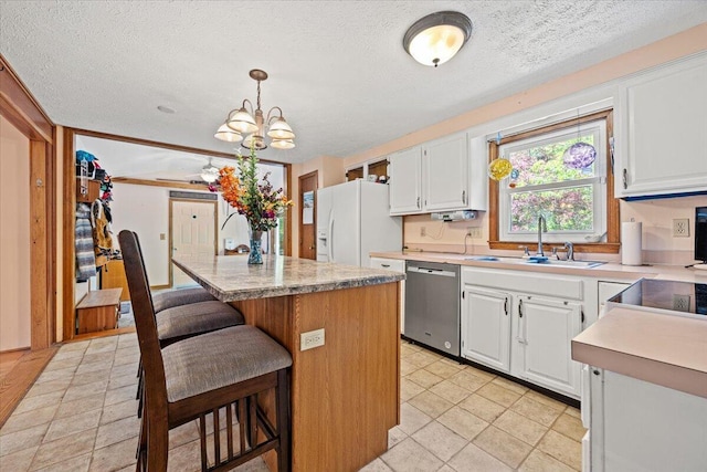 2 Blueberry Pines Dr, Kennebunk, ME 04043 - kitchen featuring stainless steel dishwasher, a sink, white refrigerator with ice dispenser, a kitchen island, and white cabinets
