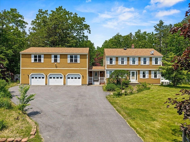 2 Blueberry Pines Dr, Kennebunk, ME 04043 - colonial-style house with asphalt driveway, a garage, a front yard, a chimney, and view of scattered trees