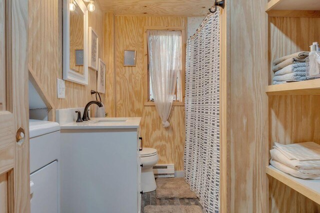 41 Sunny Ln, Sanford, ME 04073 - bathroom with a baseboard heating unit, toilet, vanity, wood walls, and a shower with shower curtain