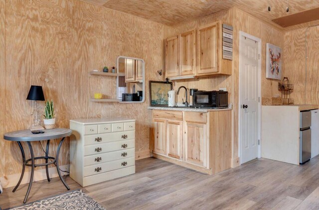 41 Sunny Ln, Sanford, ME 04073 - kitchen with black microwave, light wood-style floors, light brown cabinetry, freestanding refrigerator, and wood walls