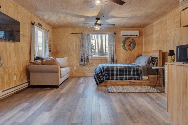 41 Sunny Ln, Sanford, ME 04073 - bedroom with a wall unit AC, wood finished floors, wooden walls, a baseboard heating unit, and ceiling fan