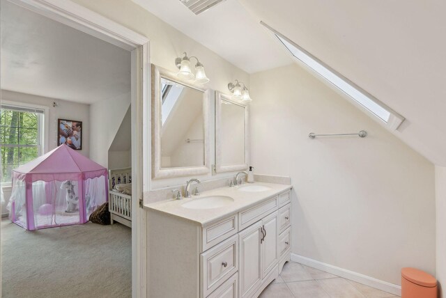 47 Old Post Ln, Sanford, ME 04073 - bathroom with a skylight, double vanity, vaulted ceiling, and baseboards