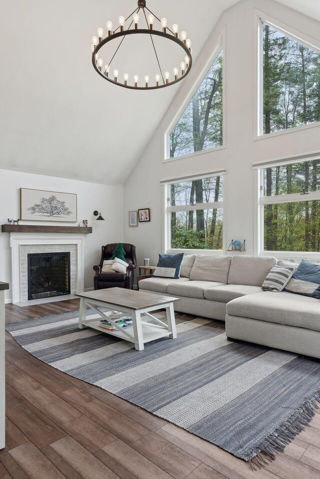 47 Old Post Ln, Sanford, ME 04073 - living room featuring high vaulted ceiling, wood finished floors, a chandelier, plenty of natural light, and a fireplace
