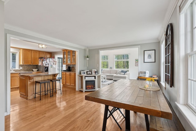 47 Old Post Ln, Sanford, ME 04073 - dining space with light wood-type flooring, crown molding, and a warm lit fireplace