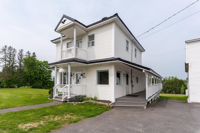 982 Main St, Grand Isle, ME 04746 - view of front of property with metal roof, a front yard, a balcony, and covered porch
