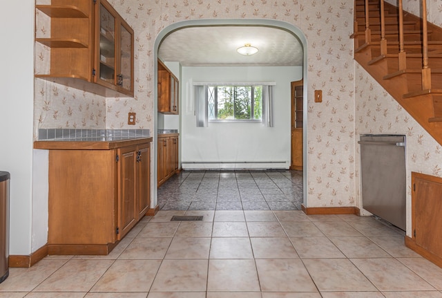 982 Main St, Grand Isle, ME 04746 - kitchen featuring wallpapered walls, brown cabinets, arched walkways, a baseboard heating unit, and tile counters