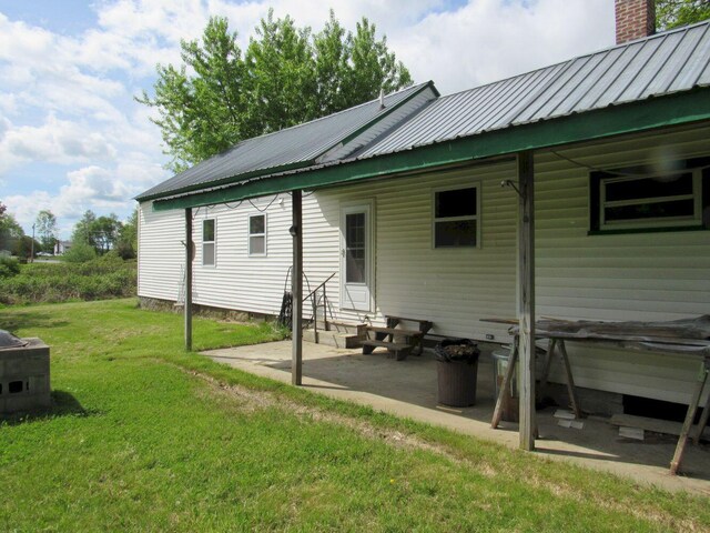 25 Moores Mill Rd, Canaan, ME 04924 - back of property featuring entry steps, a patio, a lawn, metal roof, and a chimney