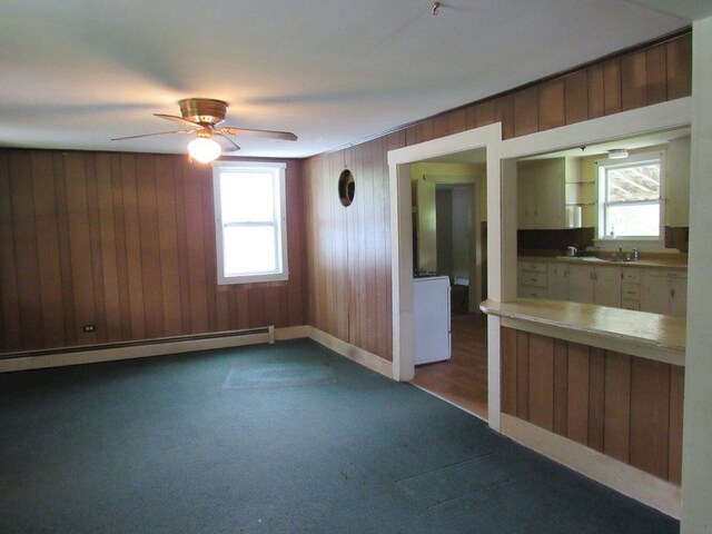25 Moores Mill Rd, Canaan, ME 04924 - unfurnished living room featuring a baseboard radiator, wood walls, dark colored carpet, and ceiling fan
