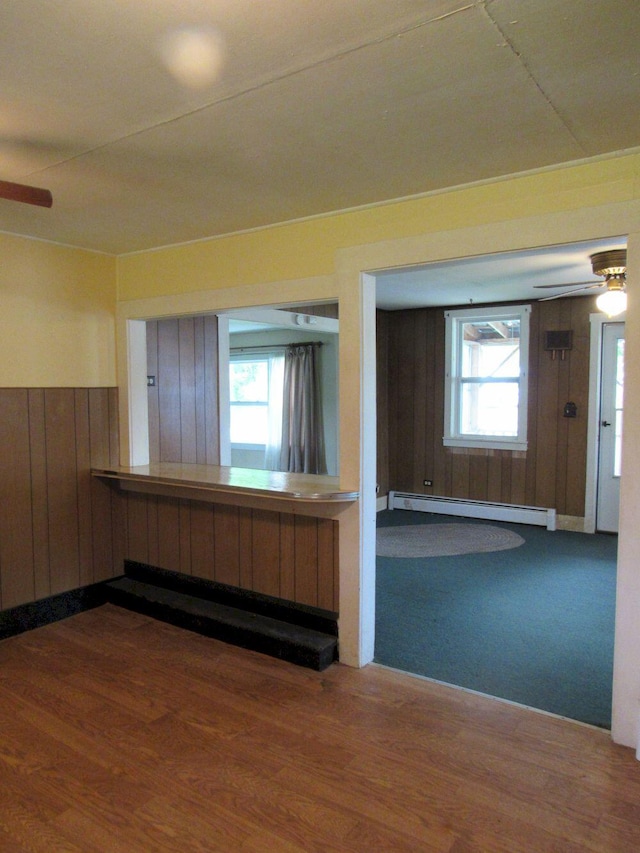 25 Moores Mill Rd, Canaan, ME 04924 - spare room with baseboard heating, a ceiling fan, wooden walls, and wood finished floors