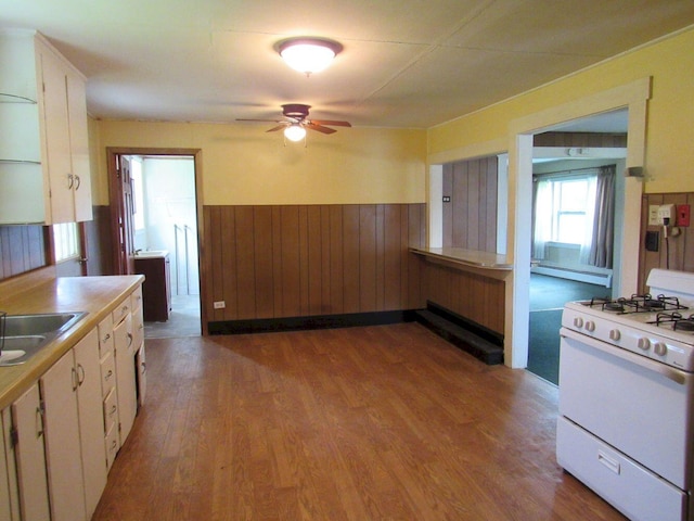 25 Moores Mill Rd, Canaan, ME 04924 - kitchen featuring white gas range, wainscoting, white cabinets, ceiling fan, and wood finished floors
