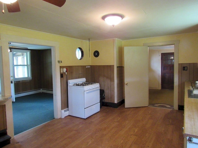 25 Moores Mill Rd, Canaan, ME 04924 - kitchen featuring white gas stove, ceiling fan, a baseboard heating unit, wood finished floors, and wooden walls