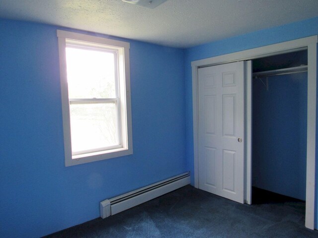 25 Moores Mill Rd, Canaan, ME 04924 - unfurnished bedroom with a baseboard heating unit, dark carpet, a closet, and a textured ceiling