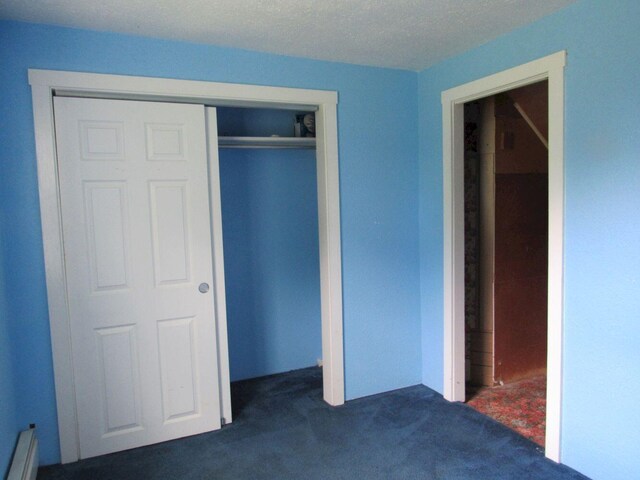 25 Moores Mill Rd, Canaan, ME 04924 - unfurnished bedroom with dark colored carpet, a baseboard heating unit, and a closet