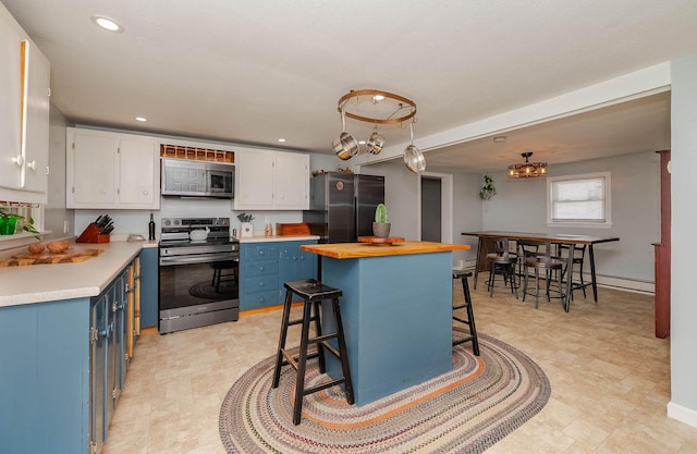 59 Milton Mills Rd, Lebanon, ME 04027 - kitchen featuring appliances with stainless steel finishes, blue cabinets, white cabinetry, a kitchen bar, and recessed lighting