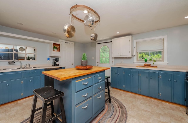 59 Milton Mills Rd, Lebanon, ME 04027 - kitchen featuring blue cabinets, a sink, a kitchen island, a breakfast bar area, and wood counters