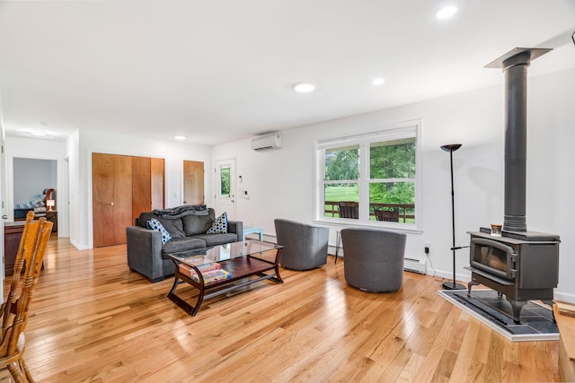 612 Airline Rd, Amherst, ME 04605 - living area featuring a wall unit AC, light wood-type flooring, a wood stove, a baseboard heating unit, and baseboard heating